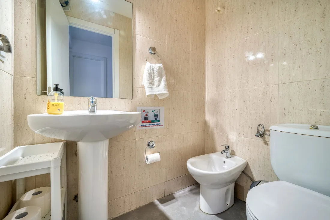 Baño con lavabo de pie, bidé y alicatado claro