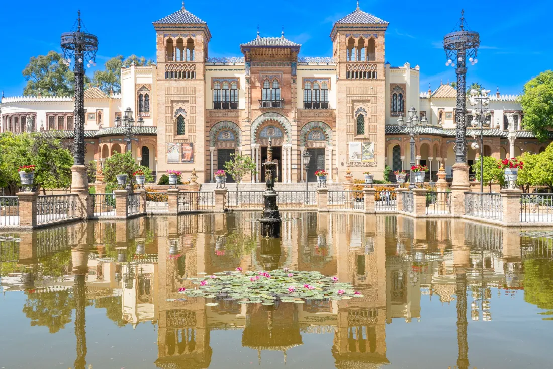 Pabellón de ladrillo y azulejo reflejado en un estanque del parque
