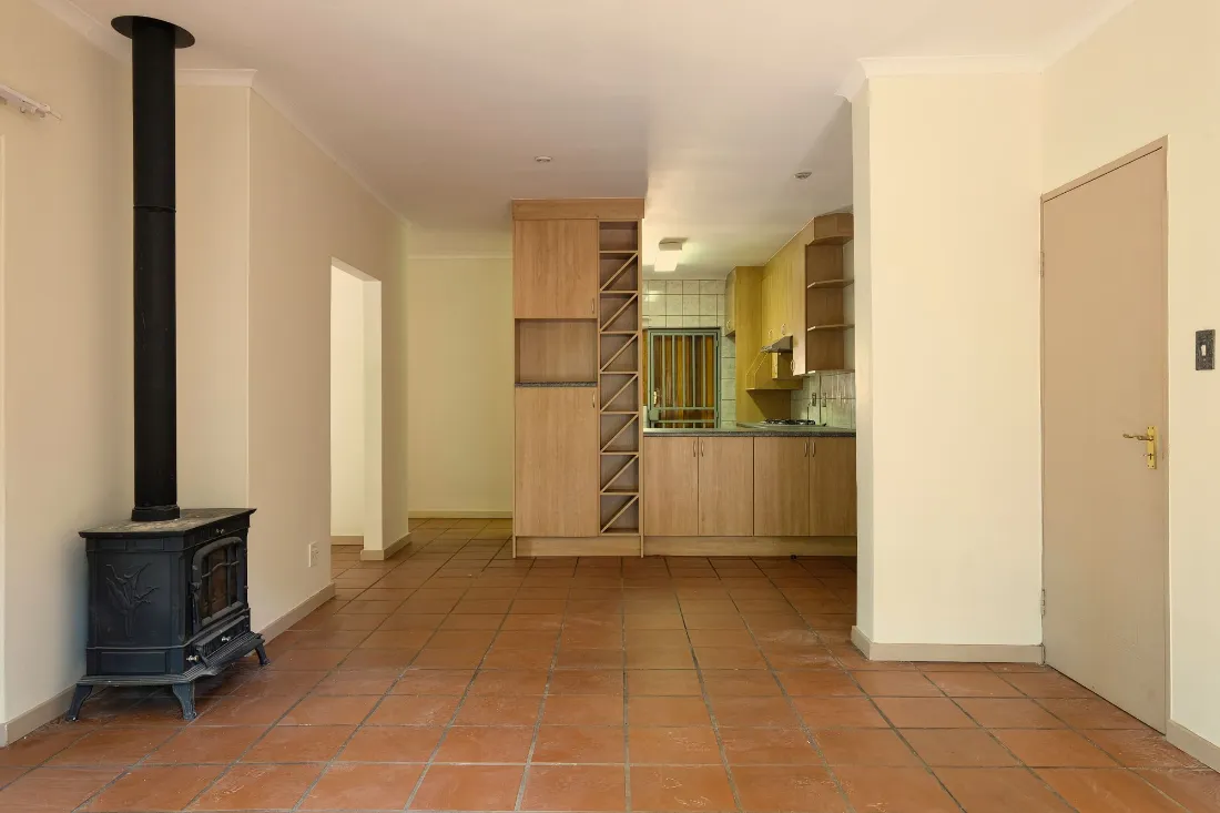 Cocina con estufa de leña y suelo de barro, vista desde el salón