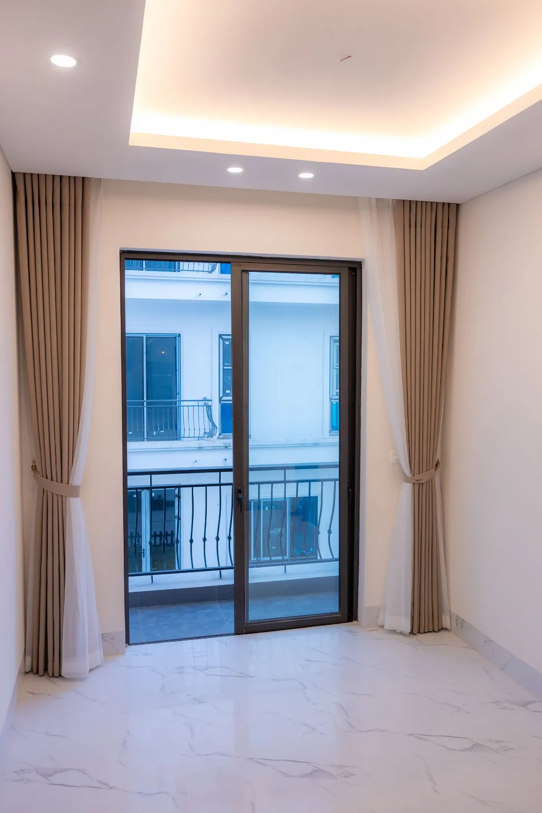 Puerta balconera con cortinas de lino y barandilla negra
