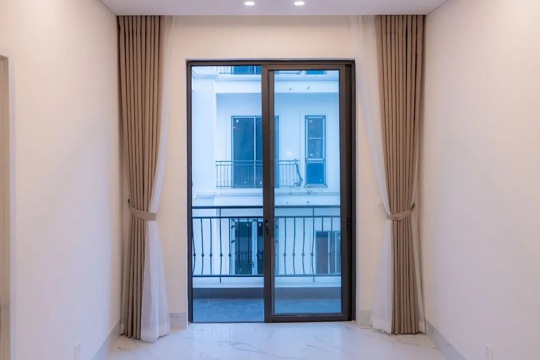 Dormitorio vacío con balcón y cortinas