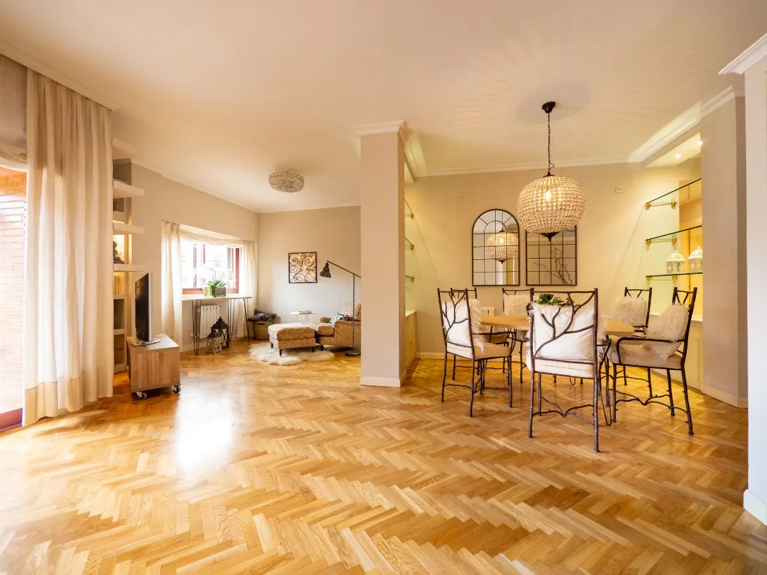 Salón comedor con parqué en espiga, lámpara de techo y mucha luz