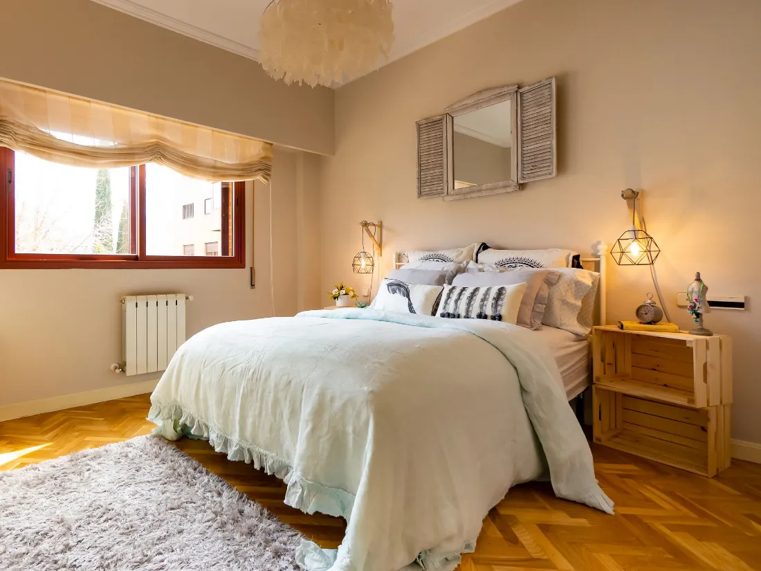 Dormitorio con cama de matrimonio, mesillas de madera y ventana con estor