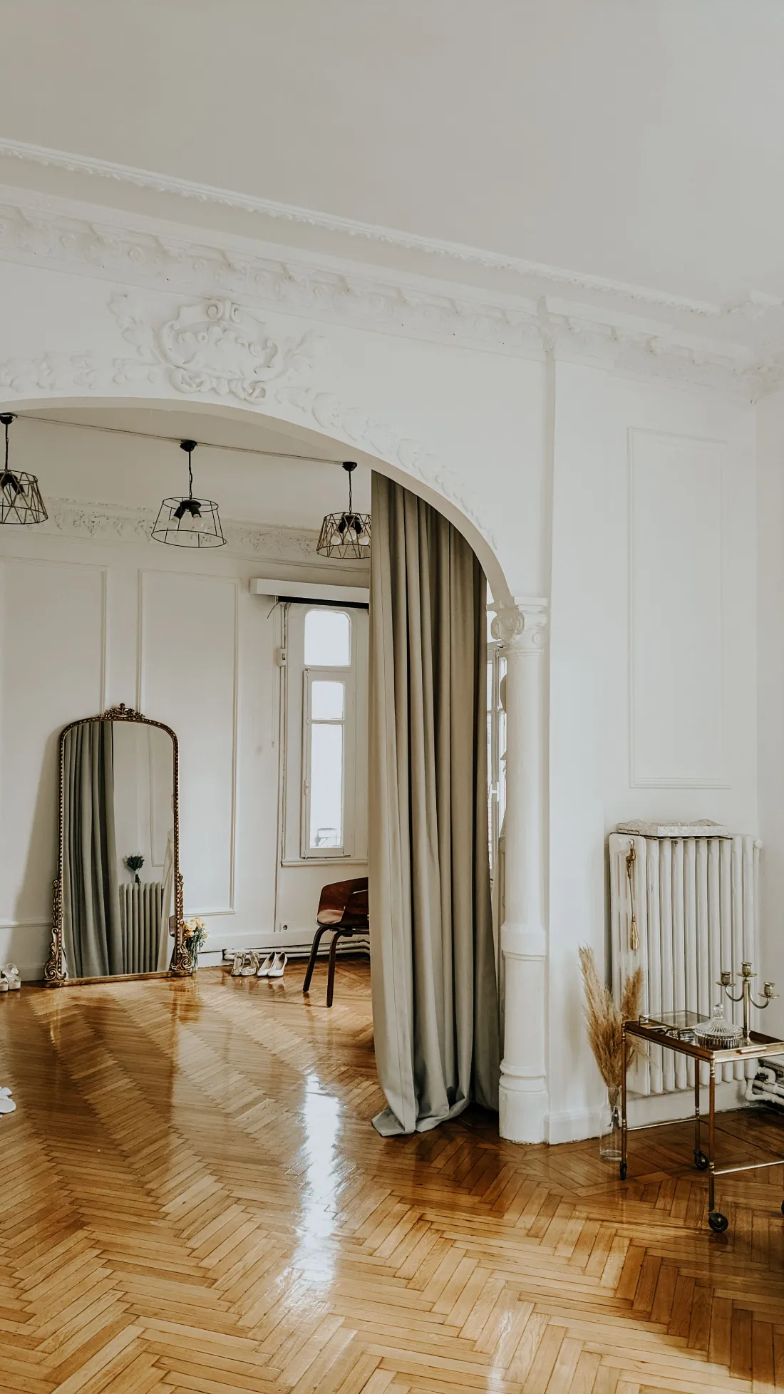 Arco con cortina de lino que separa el dormitorio, con un espejo de pie al lado