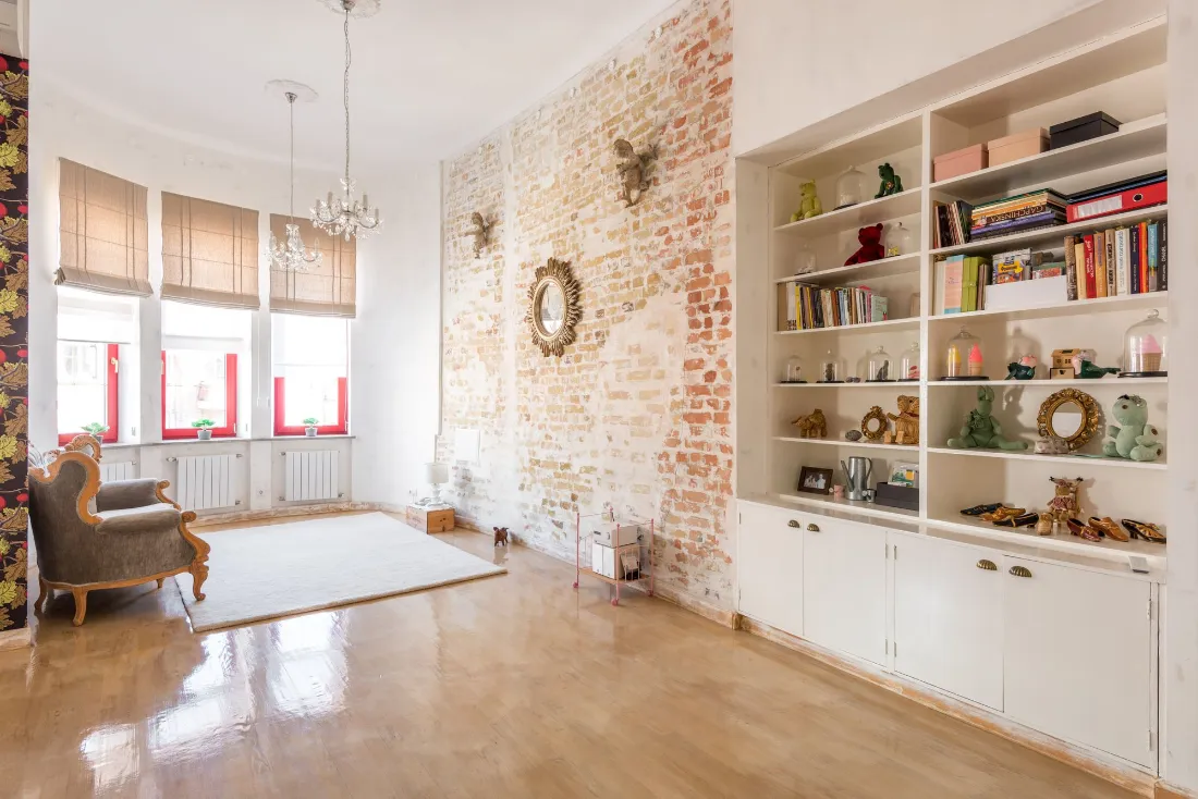 Salón con librería blanca empotrada, pared de ladrillo visto y lámpara de araña