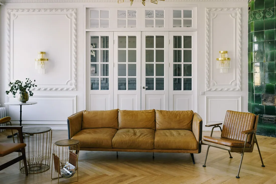 Otra vista del salón: sofá, butaca de madera, lámparas doradas y una pared de azulejo verde