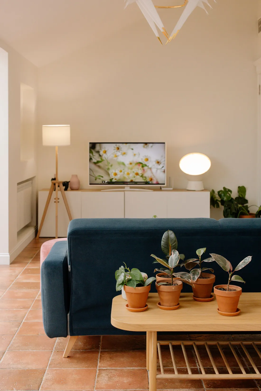Cocina de madera clara con taburetes rosas y el sofá azul delante